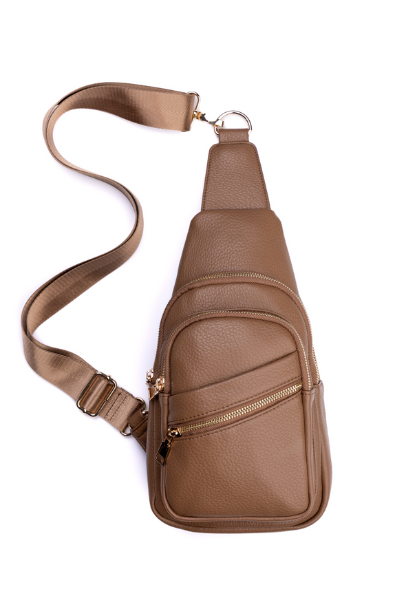 Taupe leather sling bag with a strap on a white background