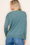 Person wearing a teal sweater and blue jeans on a plain background