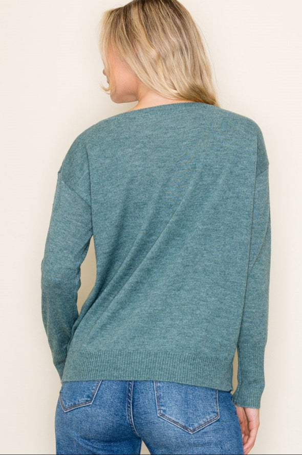 Person wearing a teal sweater and blue jeans on a plain background
